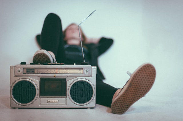 Una persona sdraiata sul letto con una radio vicino ai piedi.