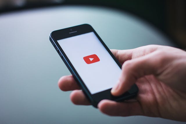 Una persona che tiene in mano uno smartphone con YouTube in caricamento sullo schermo.