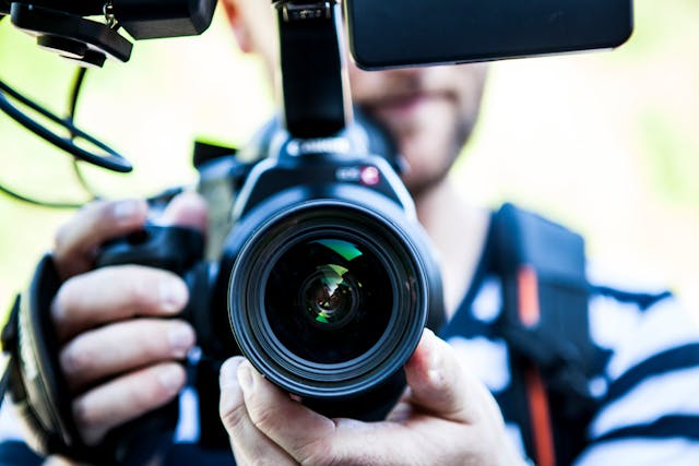 Una persona che tiene in mano una fotocamera DSLR.