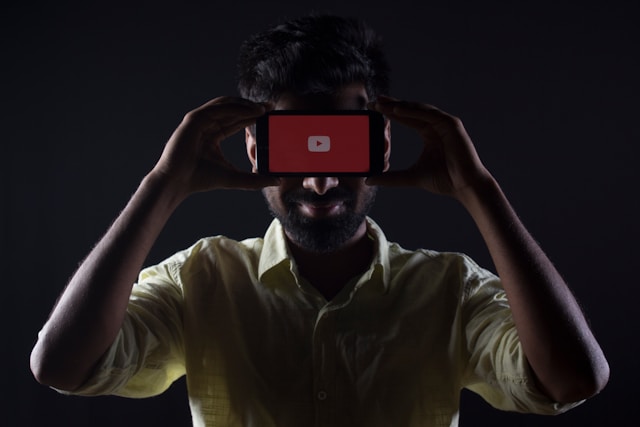 Una persona che tiene in mano uno smartphone con YouTube in caricamento sullo schermo.