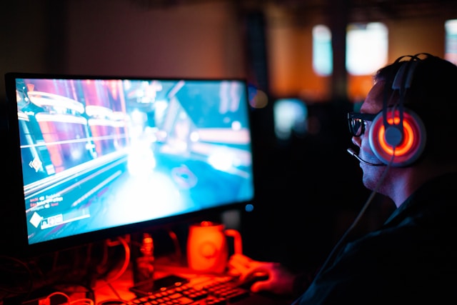 Una persona con le cuffie che gioca a un videogioco sul proprio desktop.