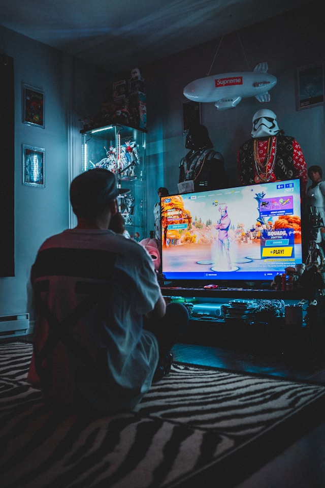 Un uomo che gioca ai videogiochi sul suo televisore in una stanza buia.