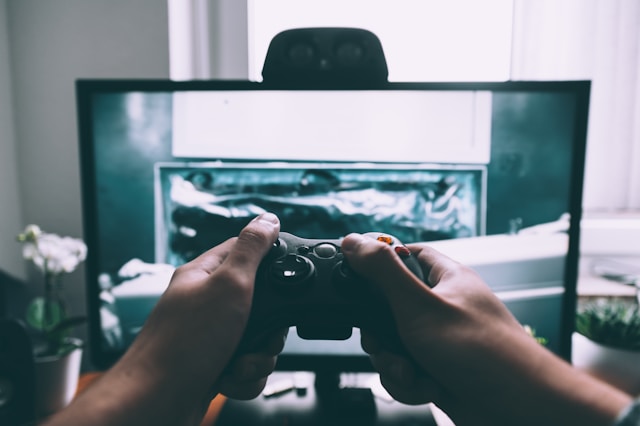 Una persona che tiene un controller di gioco davanti al televisore.