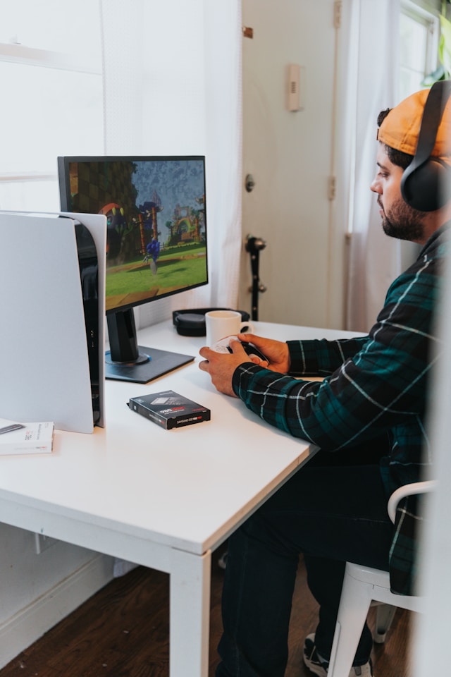 Un uomo seduto alla scrivania mentre gioca ai videogiochi al computer.