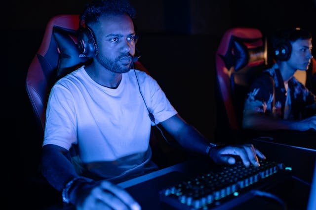 Una persona seduta a un computer da gioco con le cuffie.