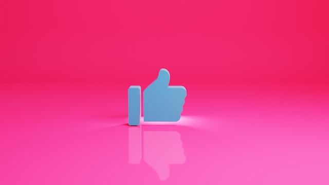 Modello 3D di un pollice in su di Facebook su sfondo rosa.