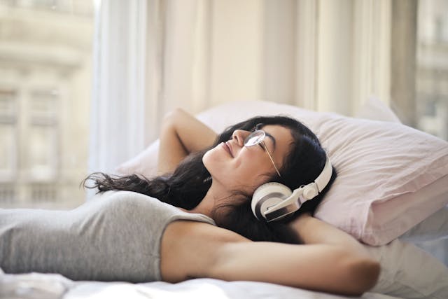 Una persona sdraiata a letto che ascolta la musica.