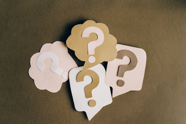Quattro punti interrogativi di carta sopra quattro corrispondenti bolle vocali.