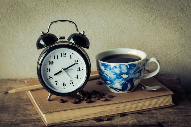 Uma chávena de café e um despertador vintage com texto em espanhol.	