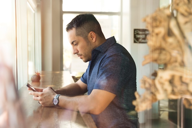 Um homem de camisa azul a utilizar o telemóvel.