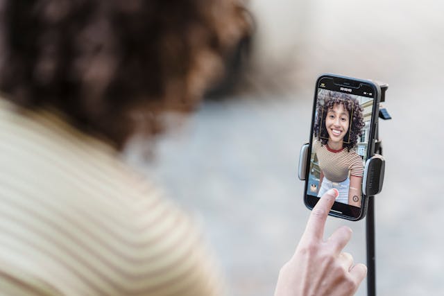 Uma mulher a sorrir e a gravar um vídeo no seu smartphone. 
