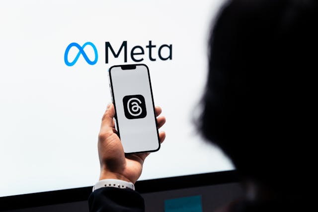 Alguém com um telemóvel a carregar Tópicos junto a um ecrã que mostra o logótipo da Meta.