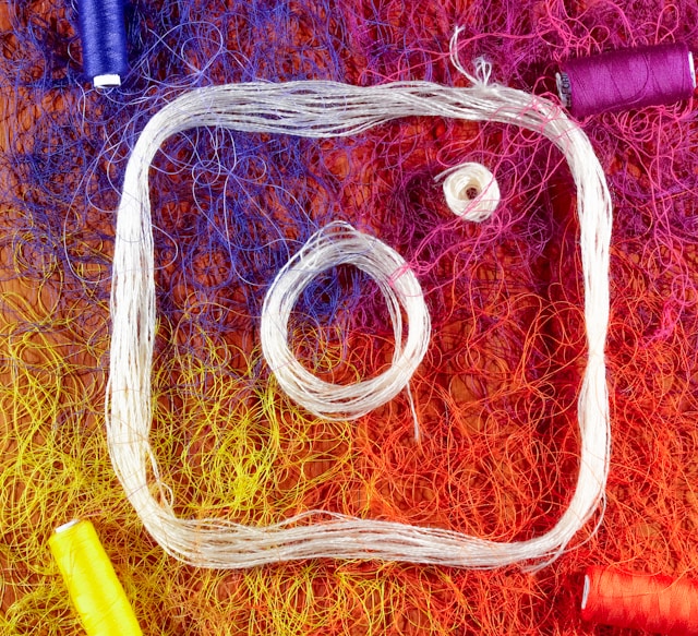 Quatro fios de cores diferentes e um fio branco que formam o logótipo do Instagram.