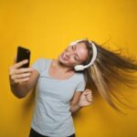 Uma pessoa a ouvir música alegremente e a olhar para o telemóvel.