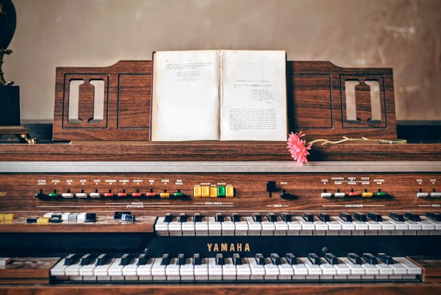 Um sintetizador de madeira com um livro aberto na estante de música.