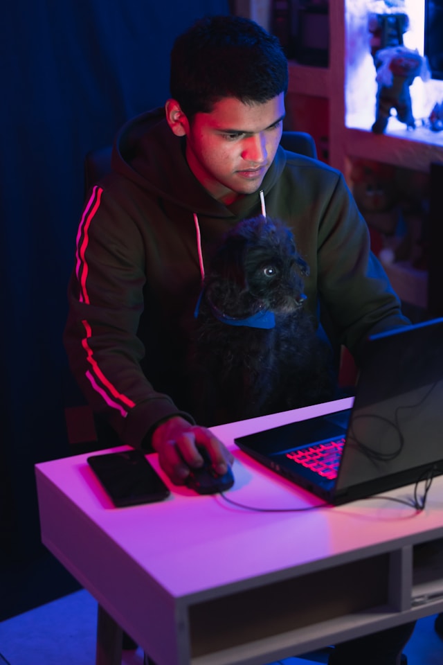 Um homem de capuz com um computador portátil preto. 