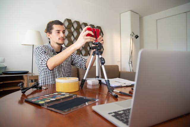 Um homem com uma camisa axadrezada a preparar a sua câmara de vlogging.