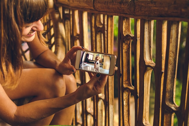 Uma mulher sorri para o seu smartphone enquanto vê um vídeo de um cão adorável.