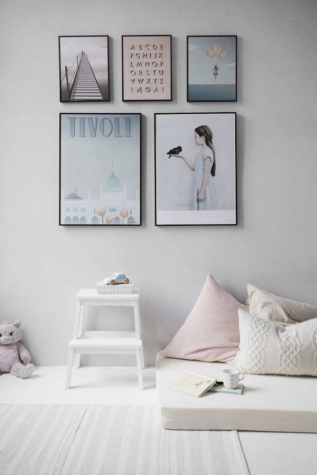 Uma fotografia estética de um quarto limpo, arrumado e minimalista com cinco posters na parede.