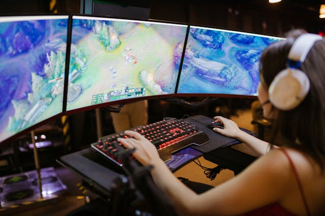 Uma pessoa com três monitores a jogar um jogo de vídeo.