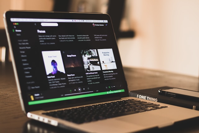 Um computador portátil que mostra a página inicial do Spotify e a sua música promovida.