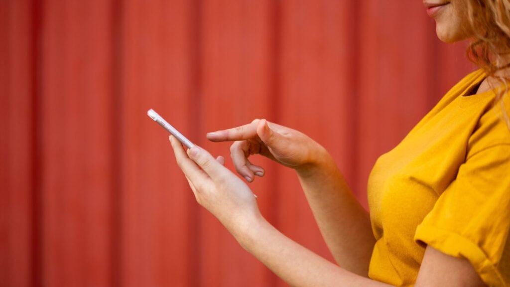 A young woman tapping on her smartphone screen.