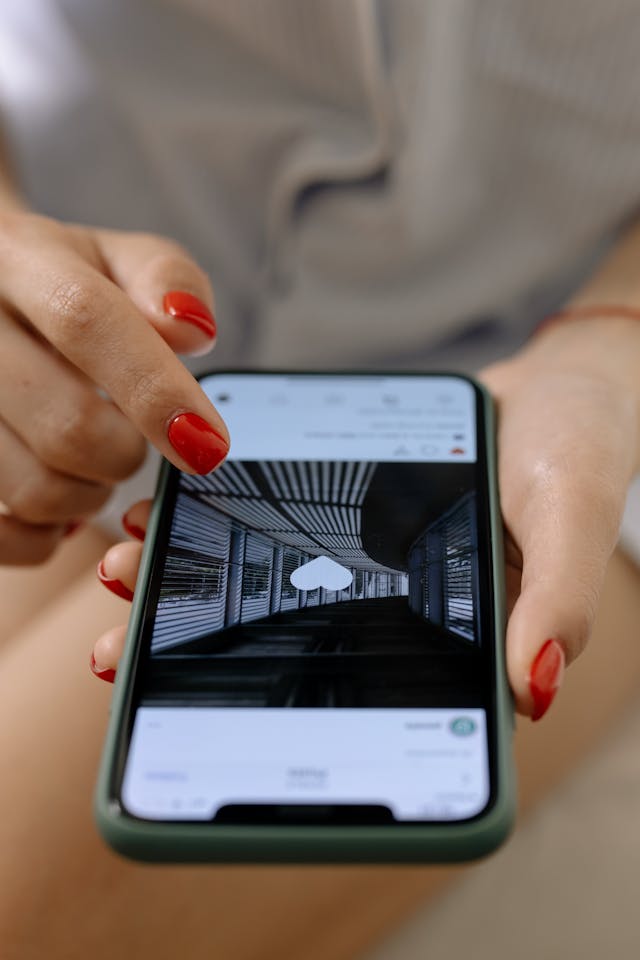 O persoană ține în mână un telefon, privind o postare de pe Instagram. Aceasta are o inimă în mijloc pentru a arăta că persoana a apreciat-o.