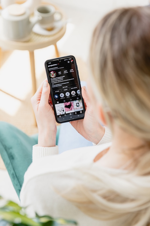 O persoană care ține în mână un telefon mobil și se uită la un cont Instagram.