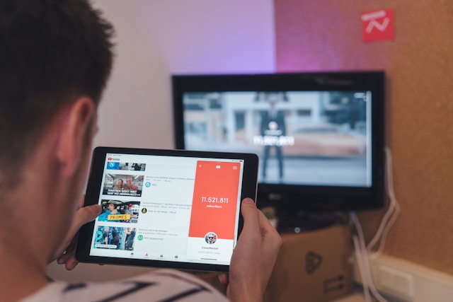 O persoană care utilizează o tabletă pentru a vizualiza numărul de abonați ai unui canal YouTube.