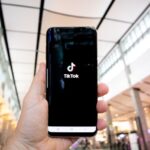 O persoană ține în mână un telefon care încarcă aplicația TikTok.