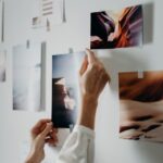 O persoană care agață fotografii imprimate pe perete.