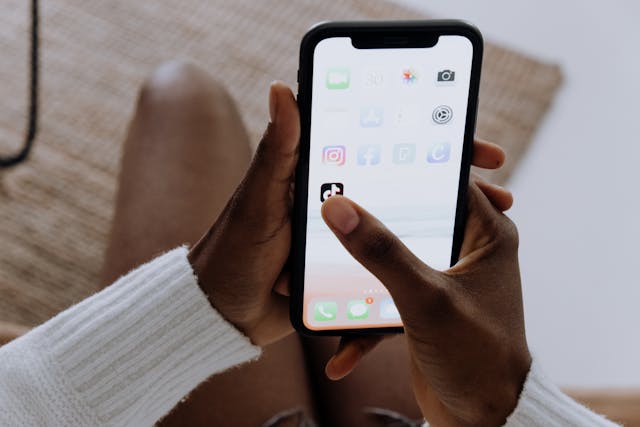 O persoană ține în mână un smartphone și apasă pe aplicația TikTok.