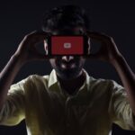 O persoană ține în mână un smartphone cu YouTube care se încarcă pe ecran.