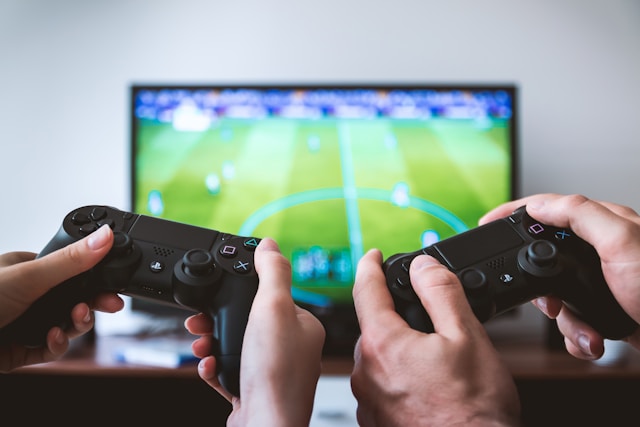 Doi oameni joacă pe o consolă PS4.