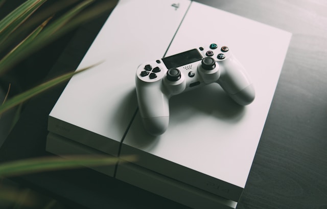Fotografiere cu focalizare selectivă a unei console PS4 albe cu un controler fără fir.