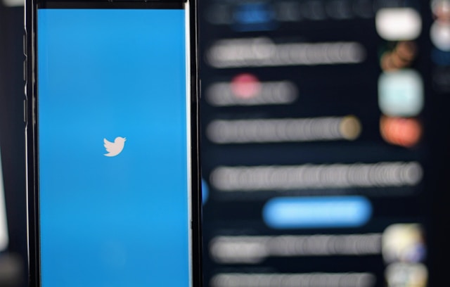 Un smartphone încarcă Twitter pe un fundal neclar.