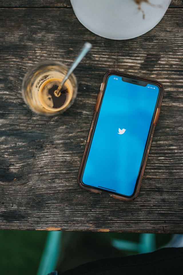 Un smartphone întins pe o suprafață de lemn cu Twitter încărcat pe ecran.