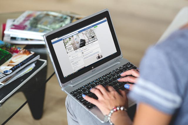 O persoană care utilizează Facebook pe laptop. 