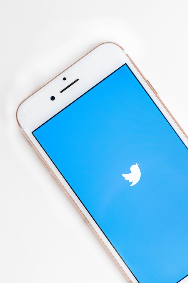 Un smartphone întins pe o suprafață albă cu Twitter încărcat pe ecran.
